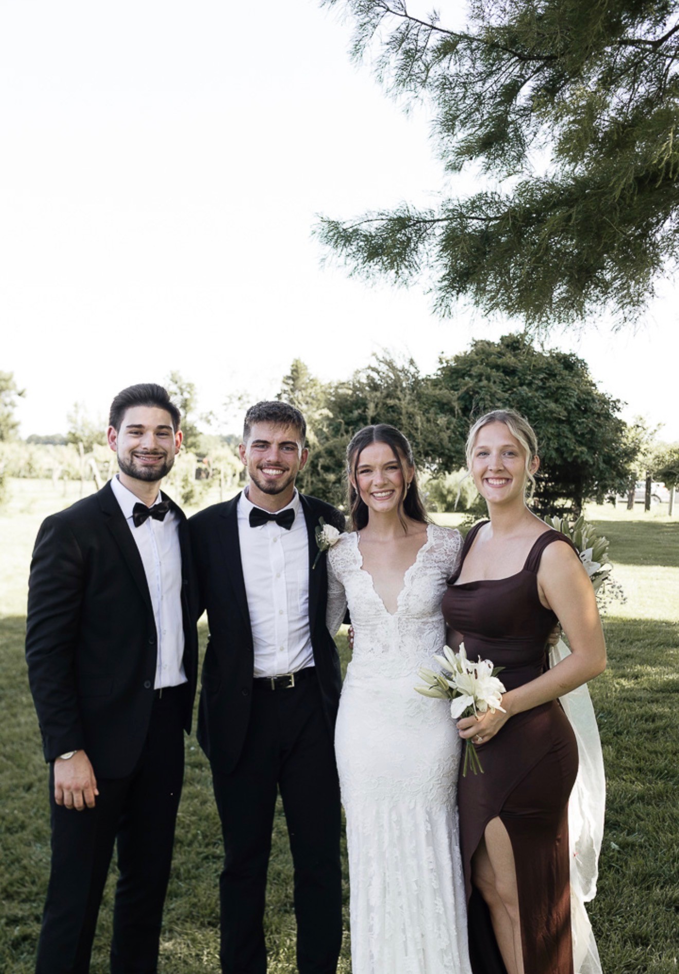 The bride and groom smiling with two friends on the lawn